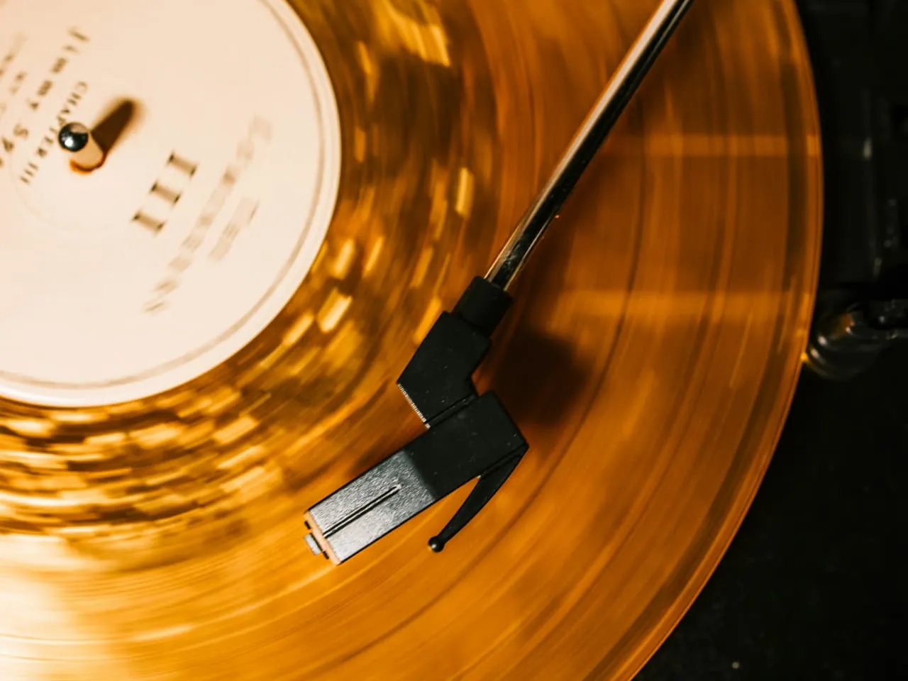 An orange vinyl record spinning on a turntable.
